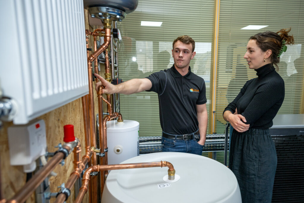 Apprentice engineer teaching student how to use heat pump controls.